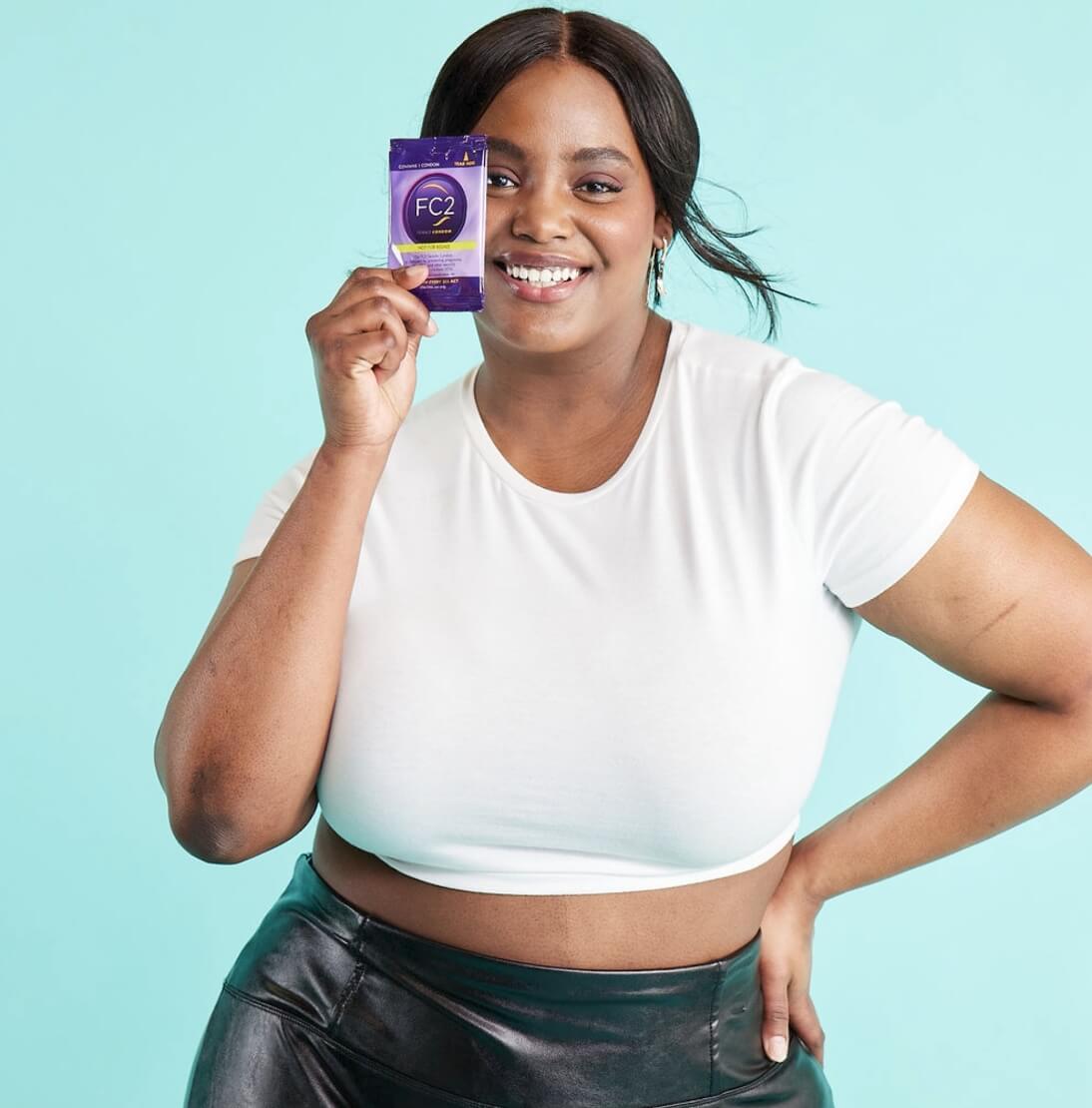 A woman smiling and showcasing a FC2 Female Condom.