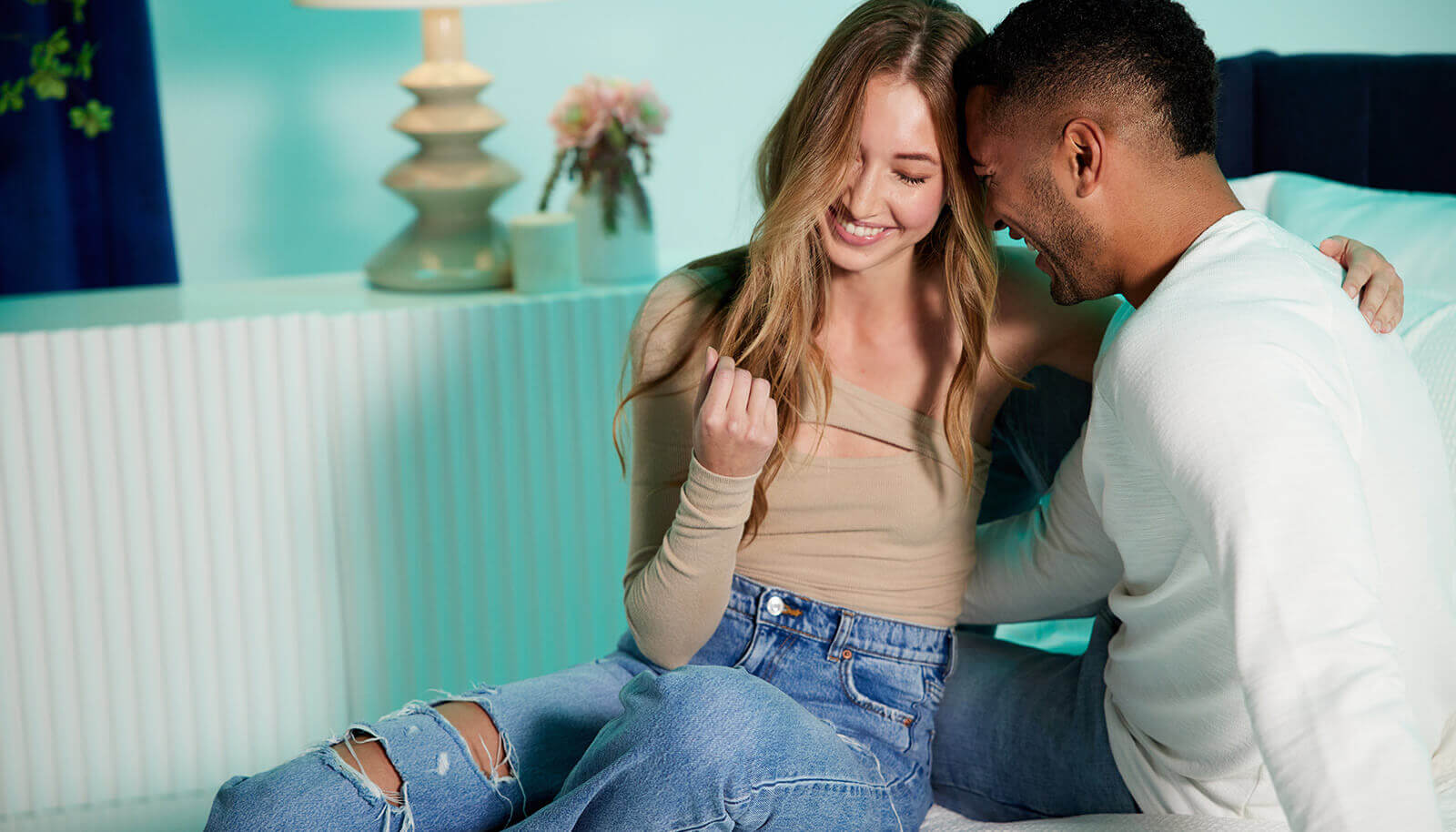 Young couple smiling and hugging on a bed